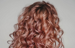 Woman with rose gold hair styled into mermaid maves